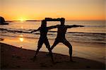 Silhouettes of people practicing yoga under the sunset