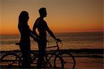 Silhouettes of couple biking together on the beach