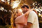 Cheerful couple about to kiss in a park