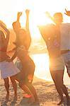 Happy friends raising arms on the beach