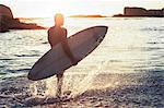 Silhouette of a surfer walking in the sea