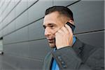 Close-up portrait of businessman standing in front of wall of building using cell phone, Mannheim, Germany