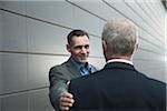 Mature businessmen standing in front of wall, talking