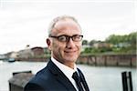 Portrait of mature businessman outdoors, wearing horn-rimmed eyeglasses, smiling at camera, Mannheim, Germany