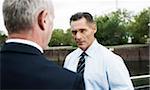 Mature businessmen standing by railing, talking, Mannheim, Germany