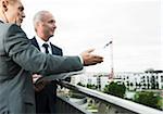 Mature businessmen standing on outdoor balcony, talking and overlooking city, Mannheim, Germany