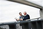 Mature businessmen standing on bridge talking, Mannheim, Germany