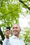 Close-up of mature man looking at smartphone in park, Mannheim, Germany