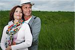 Close-up portrait of mature couple standing in field of grass, embracing, Germany