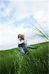 Mature couple in field of grass, man giving piggyback ride to woman, Germany