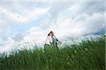 Mature couple walking in field of grass, Germany