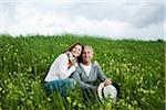 Portrait of mature couple sitting in field of grass, embracing, Germany