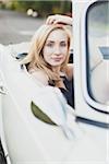 Blonde teenage girl in passenger seat of vintage 1966 Triumph