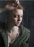 Portrait of teenage girl leaning against window, wet with raindrops