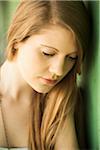 Close-up portrait of young woman with long hair outdoors, looking downwards