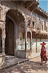 Woman Carrying Basket on Head Walking Past Traditional Haveli in Old District of Nawalgarh, Rajasthan, India