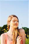 Portrait of young woman sitting in field enjoying nature, Germany