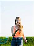 Young woman walking in field playing with bubbles, Germany