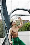 Mature man standing on outdoor basketball court pouring bottle of water on face, Germany