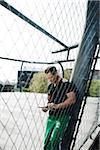 Mature man standing on outdoor basketball court looking at tablet computer, Germany