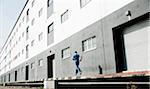 Backview of mature man running along loading dock next to warehouse, Mannheim, Germany