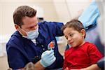 Boy patient receiving complimentary lollipop after a dental checkup by male dentist.