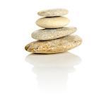 Pile of four pebble stones stacked in a pyramid isolated on a white reflective surface