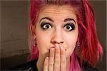 Young punk rocker in pink hair with hand on mouth