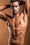 Shirtless male model posing over a brown background