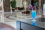 alcoholic cocktail of blue color is in the lobby of prestige hotel