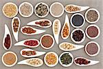 Large nut and seed food selection in porcelain bowls over hessian background.