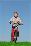 Happy young girl on bike on green meadow