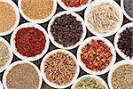 Spice and herb selection in white porcelain bowls over bamboo background.