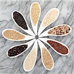 Rice grain selection in white porcelain bowls over marble background.