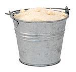 Golden caster sugar in a miniature metal bucket, isolated on a white background