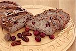 Cranberry and pecan bread on a beech wood bread board over oak background.