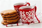 Closeup of Christmas mulled wine in two small red cups and gingerbread against white background