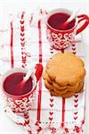 Christmas mulled wine in two small red cups and gingerbread against white background