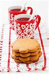 Gingerbread biscuits and two small cups of Christmas mulled wine resting on teatowel against white background