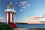 a red and white lighthouse at dusk, overlooking cliffs