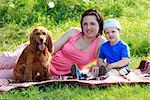 Yong mother with toddler and dog sitting on rad on nature