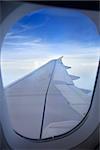 view of plane's wing from inside window cabin while plane is on flight. noise might viewable by high ISO