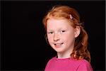 Portrait of a young red-haired girl on black background