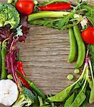 Frame of fresh vegetables and herbs on a wooden background.