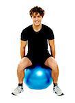 Handsome guy seated on exercise ball over white background