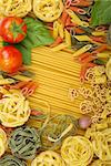 Overhead various Italian pasta background with tomatoes, basil and garlic