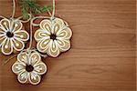 Gingerbread cookies with twig hanging over wooden background