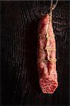 Hanging salami sausage on an old wooden board.