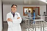 Doctor standing in the hallway while crossing his arms and looking serious