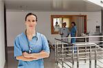 Doctor standing in the hallway of a hospital while crossing her arms